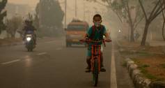 A boy cycles in Indonesia in smog