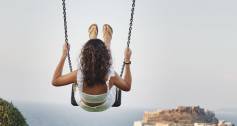 Woman swinging high above horizon