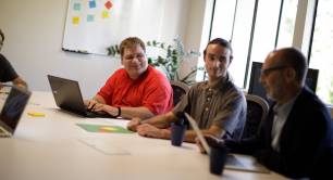 Three auticon consultants sitting at desk