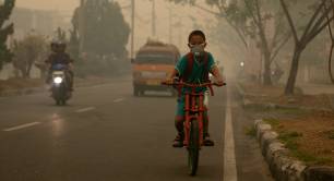 A boy cycles in Indonesia in smog