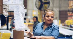 Woman working in a warehouse supported by First Step Staffing. The non-profit helps people facing barriers to employment find jobs