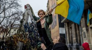 Volunteers raise a Ukrainian flag while making camouflage nets outside the Ivanychuk Library in Lviv, Ukraine, on Tuesday, March 1, 2022.