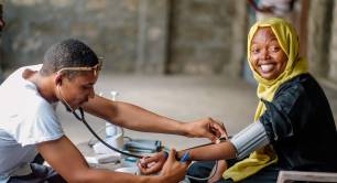 Smiling woman has her blood pressure checked by a doctor