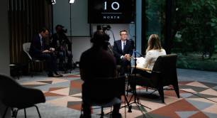 Andy Burnham sat on a chair in front of cameras and journalists next to a "Number 10 North" sign