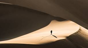Solitary figure walking across desert 