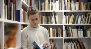 Student looking at a book in library