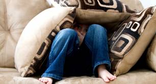 Child hiding under cushions