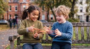 Two smiling children play together on a bench