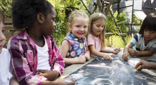 group of diverse children drawing on chalkboard together