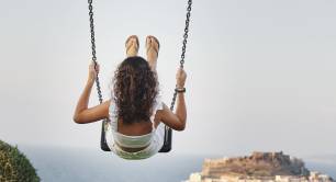 Woman swinging high above horizon